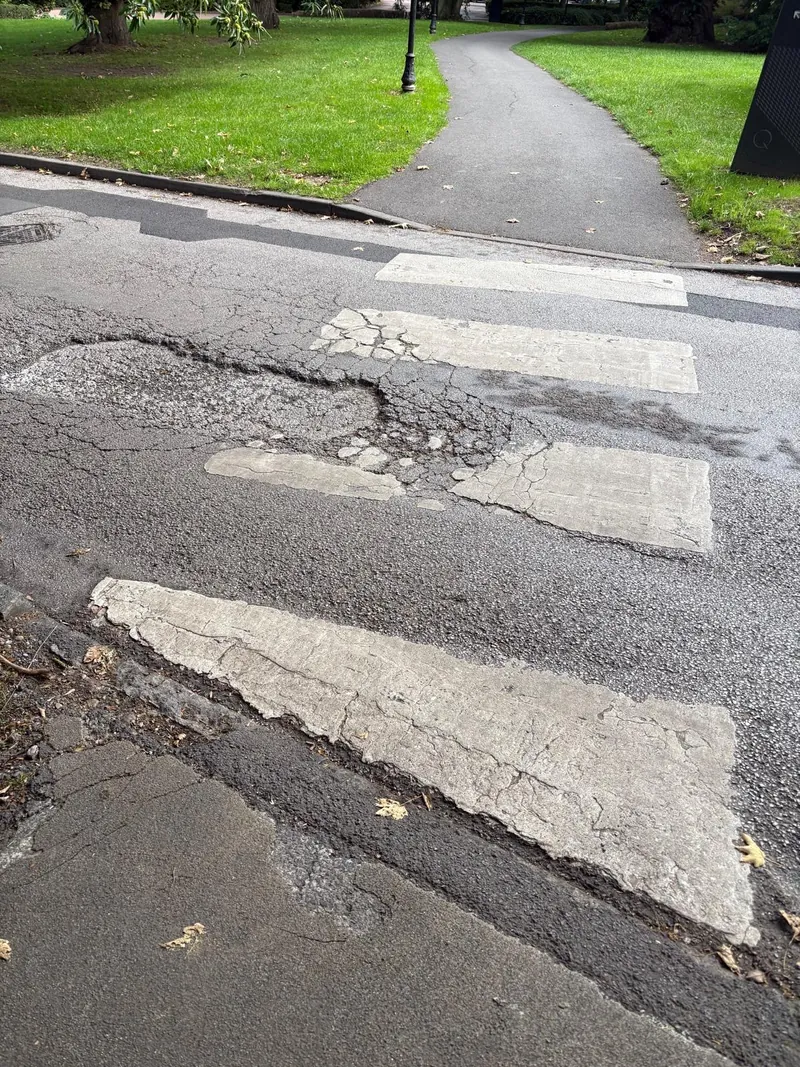 Pothole and failed asphalt at a pedestrian crossing before repair