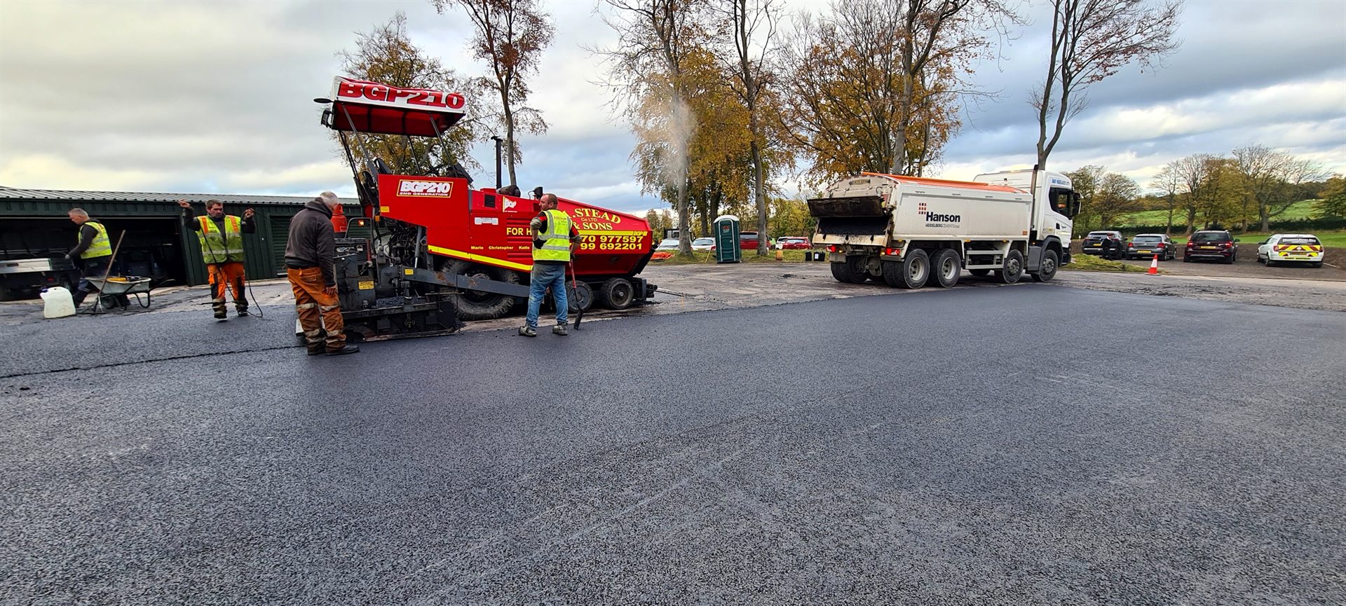 Paving train and surfacing crew machine-laying asphalt at Sand Moor Golf Club